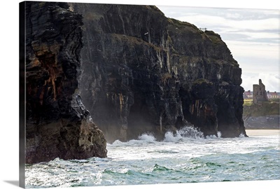 Cliffs with waves crashing into the rock with ruined castle turret, Ballybunion, Ireland