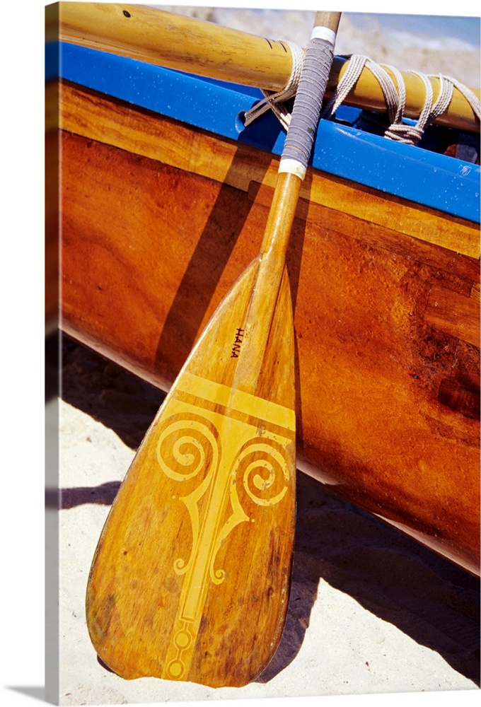 Close-Up Detail Of Wooden Paddle And Outrigger Canoe On Beach