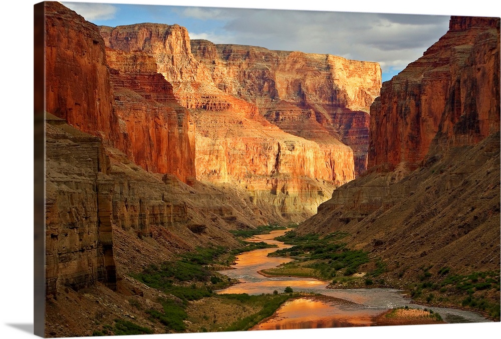 Large wall art of a river winding through the bottom of the Grand Canyon while the sides of the canyons cast shadows in th...