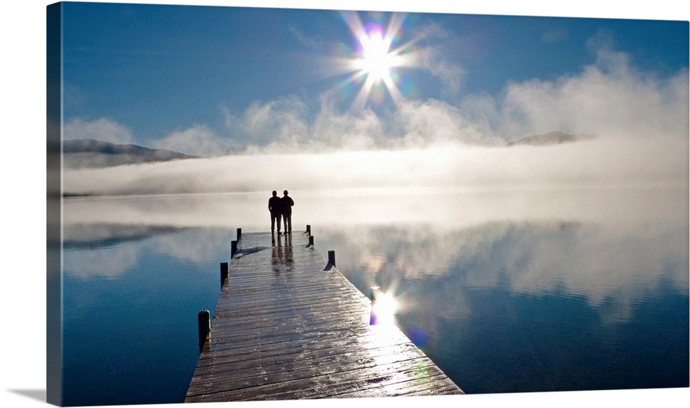 Couple standing on a dock and silhoutted against the fog lifting from Lake Whatcom during Winter, Bellingham Washington, USA