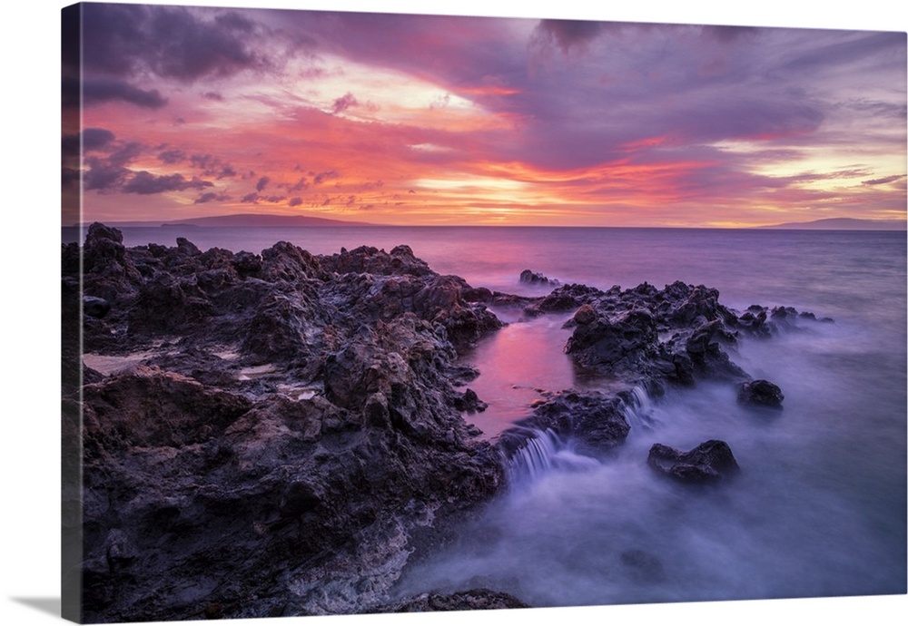 Dramatic sunset over the ocean with waterfalls along the rugged coastline; Wailea, Maui, Hawaii, United States of America