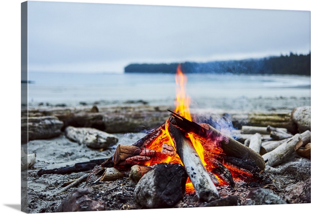A fire on the beach with the ocean and coastline in the background, Cape Scott Provincial Park; British Columbia, Canada