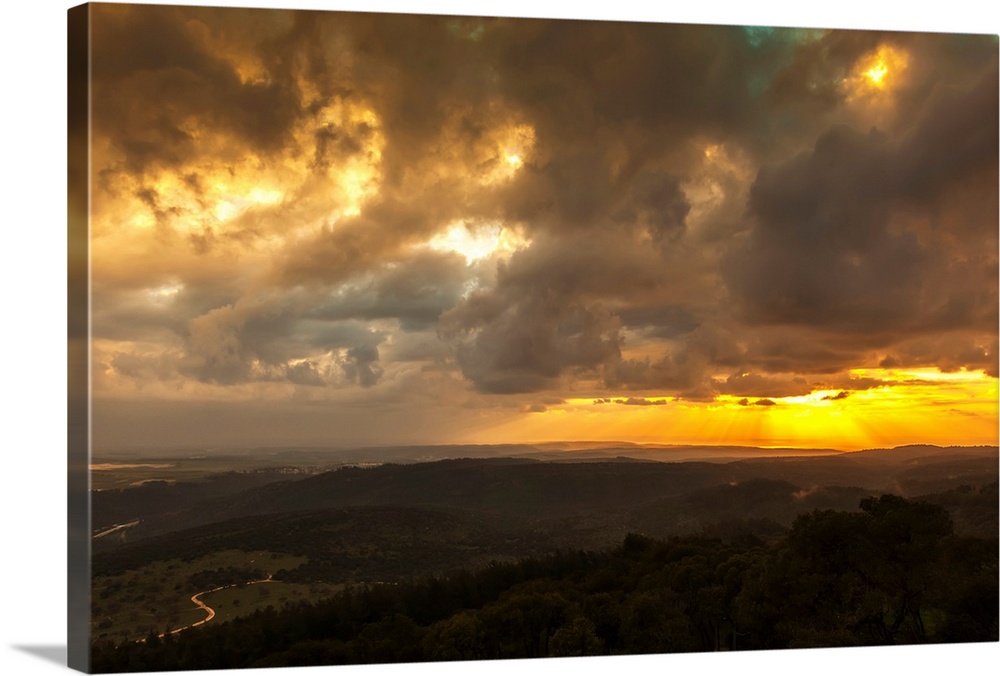 Golden sunset with glowing clouds and silhouetted landscape. Israel.
