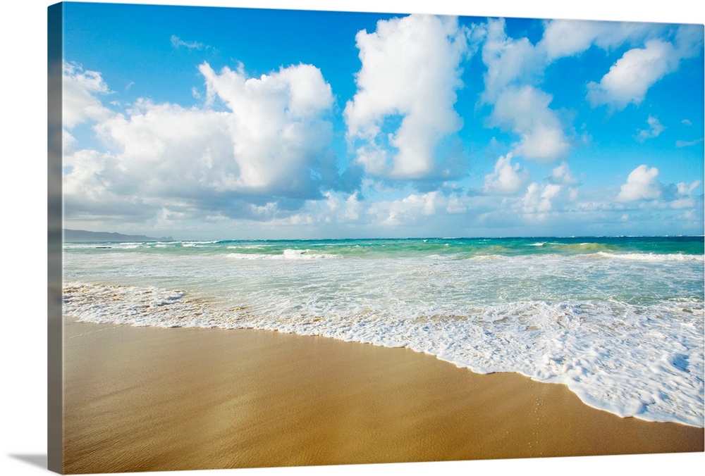 A breathtaking view of the ocean from the sands in Hawaii with large white clouds above.