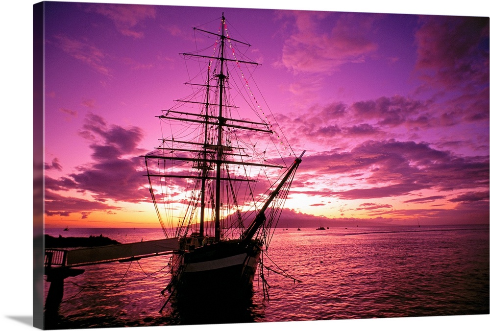 Landscape photograph of a silhouetted Carthaginian ship in the waters of Lahaina Harbor, beneath a vibrant sky as the sun ...