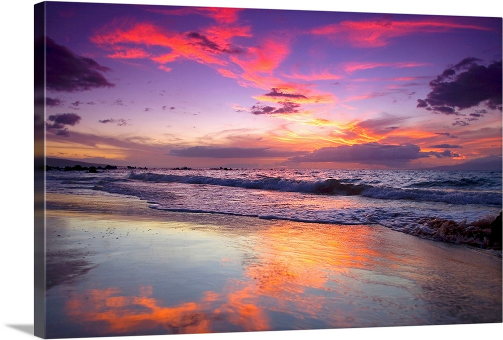 Large photograph of waves crashing on Maui shore  as the sun sets behind the clouds.