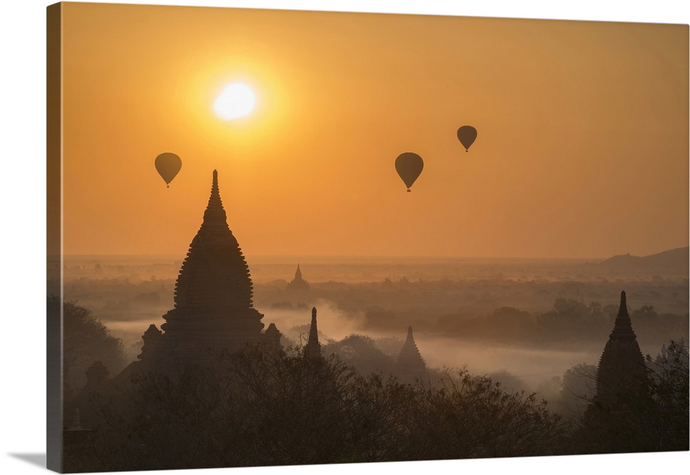 Hot air balloons flying over temples on a misty morning at Bagan.