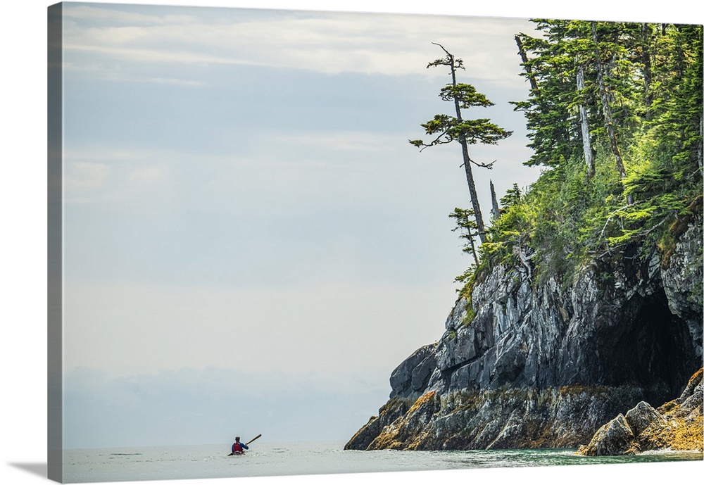 Kayaker paddling through the calm waters in the beautiful scenery of Prince William Sound; Alaska, United States of America