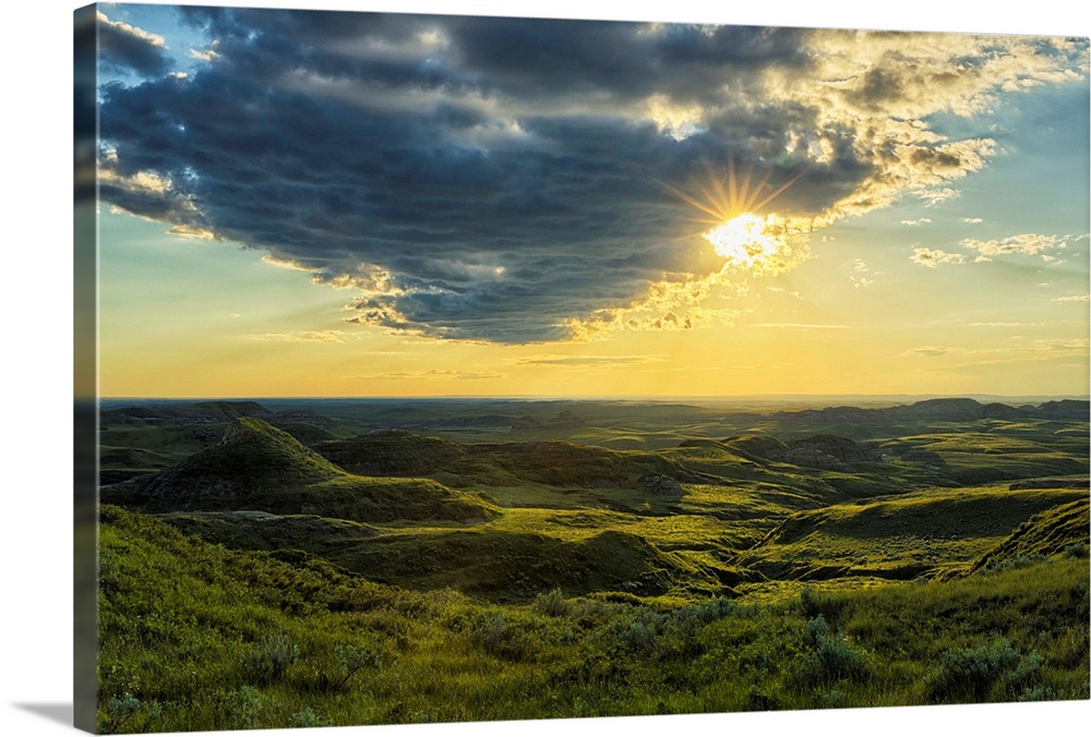The sun shines through a cloud over the Killdeer Badlands, Grasslands National Park, Saskatchewan, Canada.