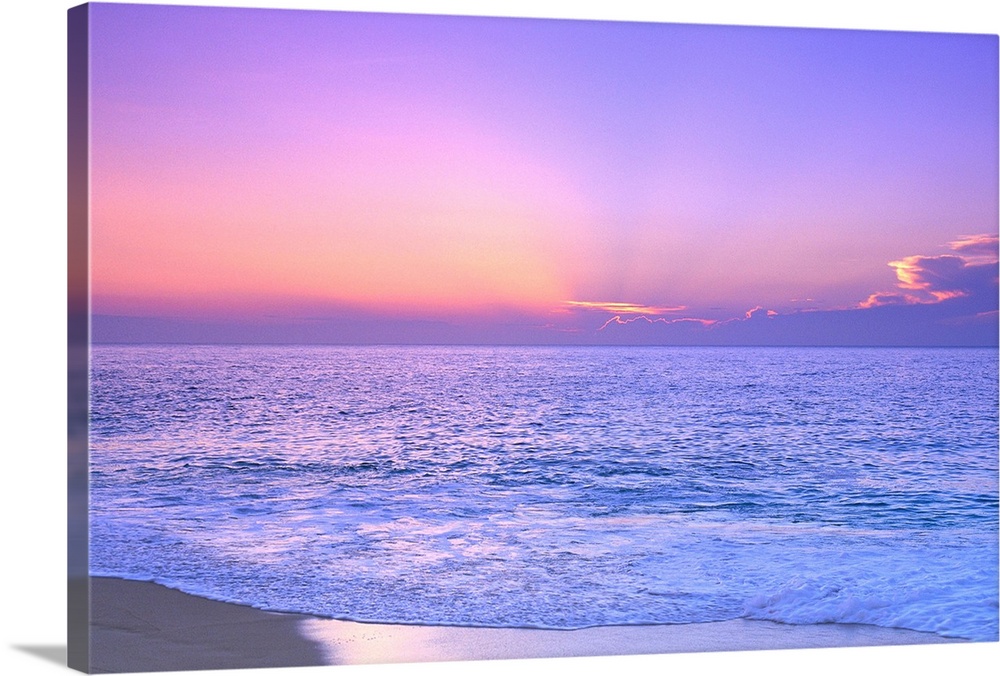 A breathtaking photograph of a sunset over the vast ocean giving the overall picture a soft colored hue.