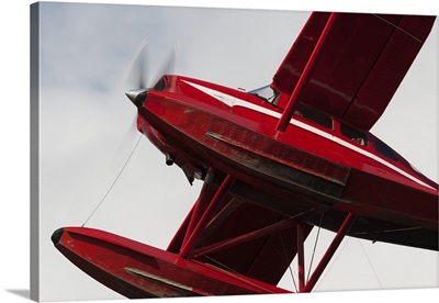 Low Angle View Of A Red Float Plane Against A Cloudy Sky; Alaska