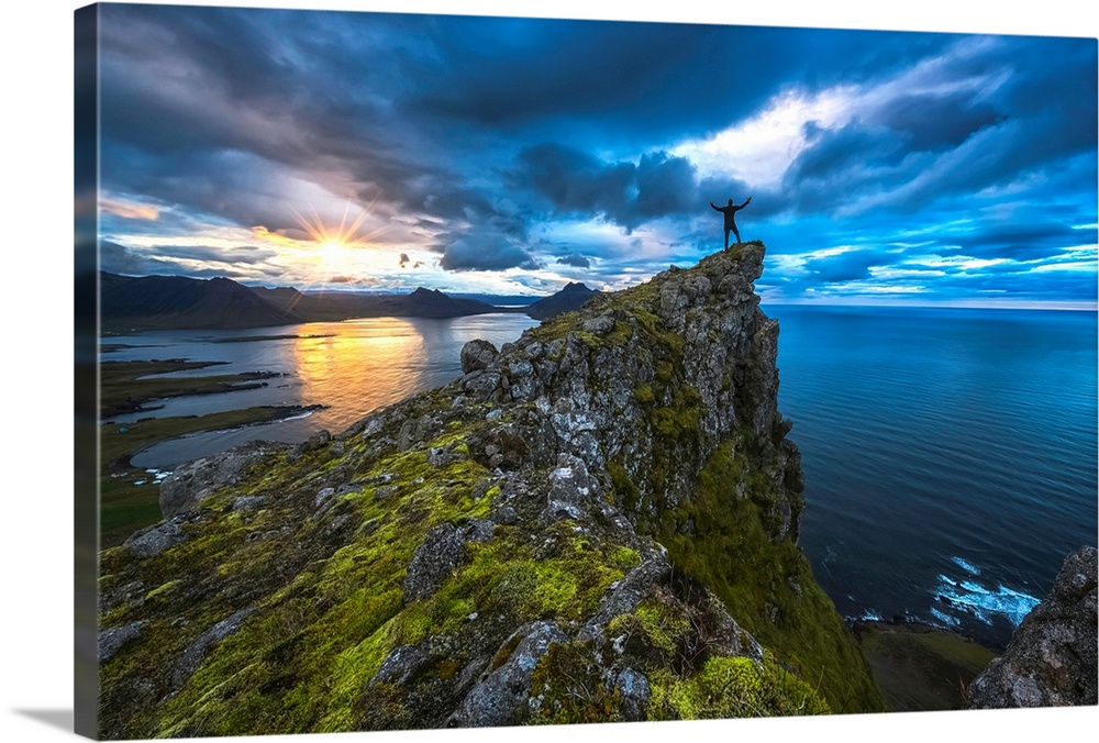 Man standing on top of a sea cliff at sunset along Iceland's Strandir Coast in the West Fjord region, Iceland.