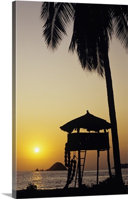 Mexico, Ixtapa Coast, Beach Bungalow And Palm Tree Silhouette At Sunset