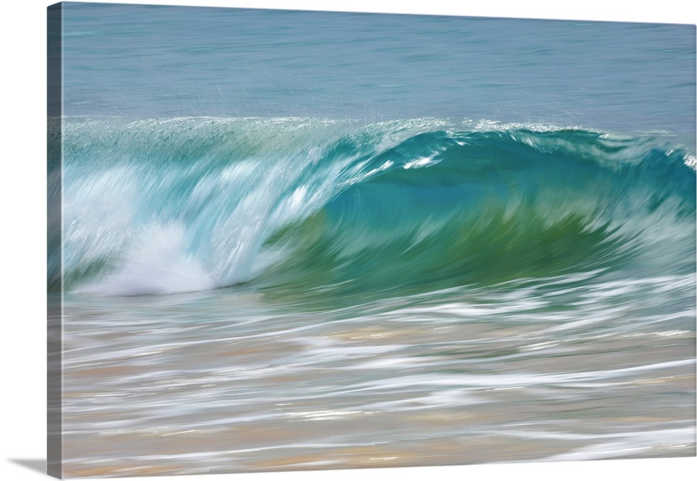 Motion blur of blue rolling waves rolling into the golden sand at the shore; Kihei, Maui, Hawaii, United States of America.