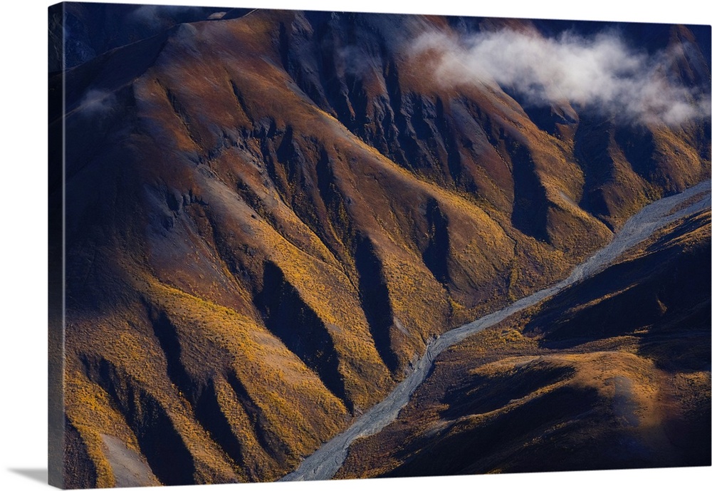 Late afternoon sun lights up the autumn colors on the slopes as nines creek flows through the mountains on its way to the ...