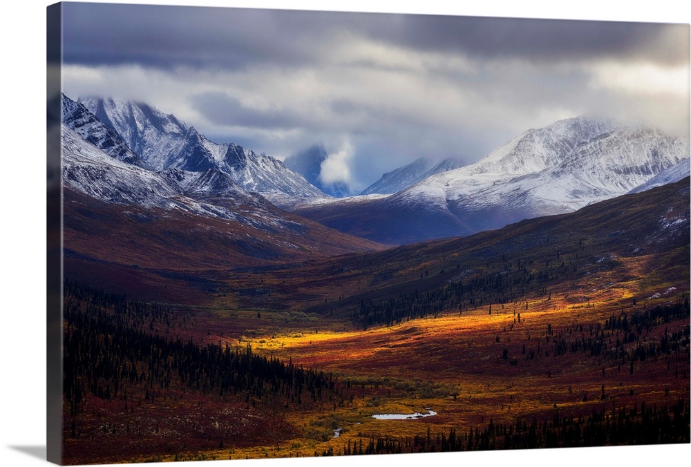 Storm clouds part allowing light to illuminate the landcape in the North Klondike Valley along the Dempster Highway in nor...