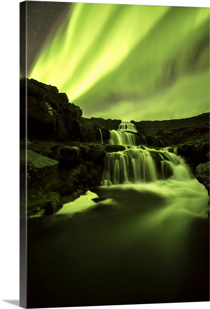 Northern Lights, or Aurora Borealis, glowing over waterfalls and a stream; Iceland