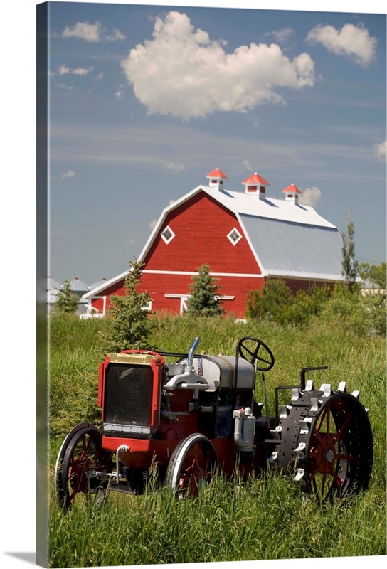 Old Red Tractor In A Field With A Red Barn In The Background; Alberta