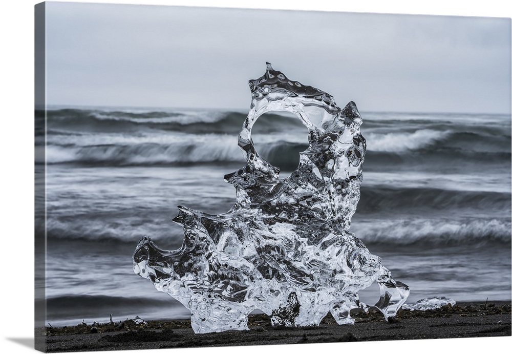 Piece of ice on diamond beach, near Jokusarlon, with the ocean behind it along the south coast of Iceland, Iceland.