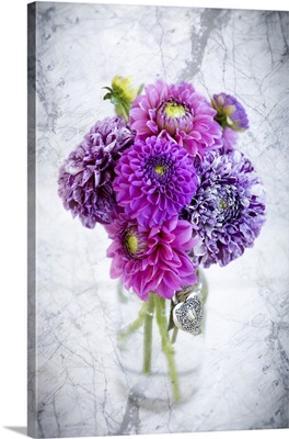 Purple marbled dahlia's arranged in a glass jar on a marble counter