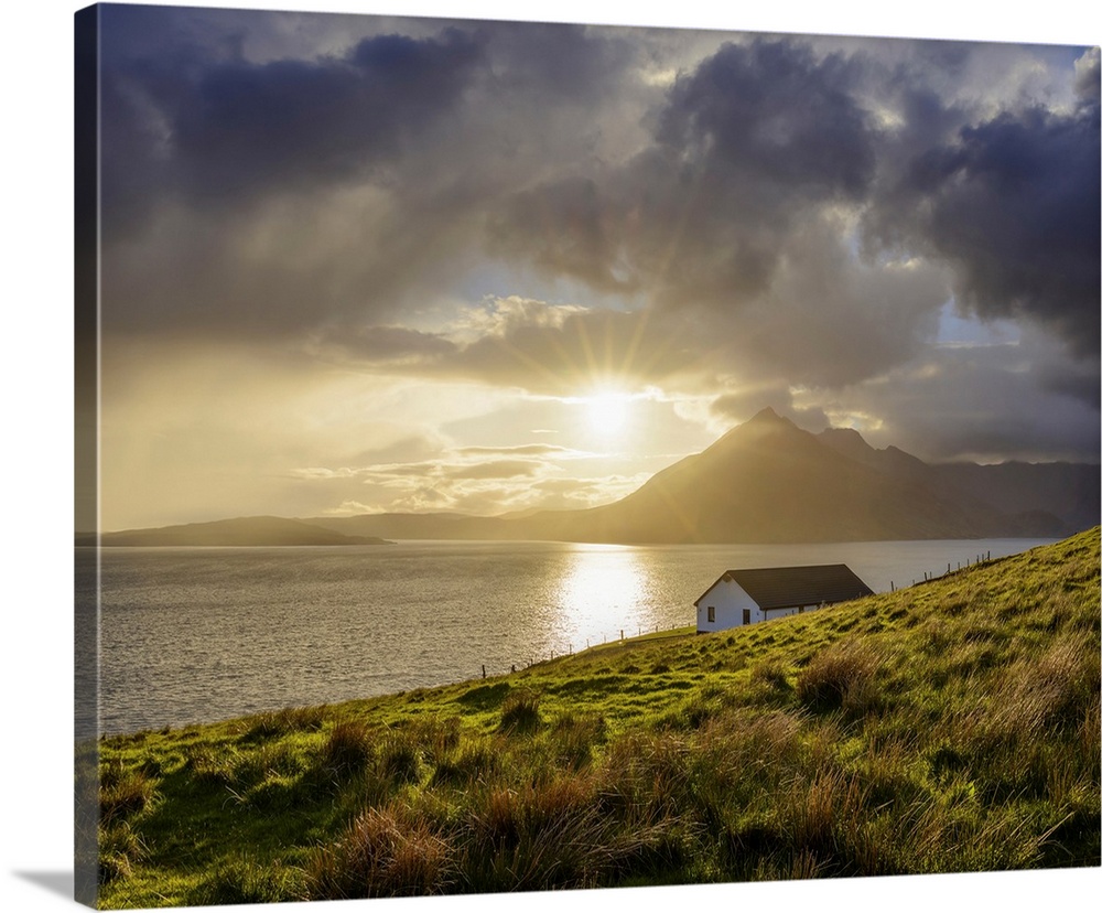 Rooftop of a house along the Scottish coast with sun shining through the dramatic clouds over Loch Scavaig on the Isle of ...