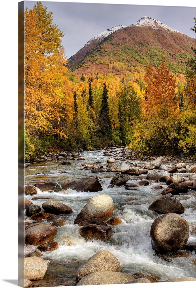 Vertical photograph on a large wall hanging of the rocky Little Susitna River leading toward a large mountain in the backg...
