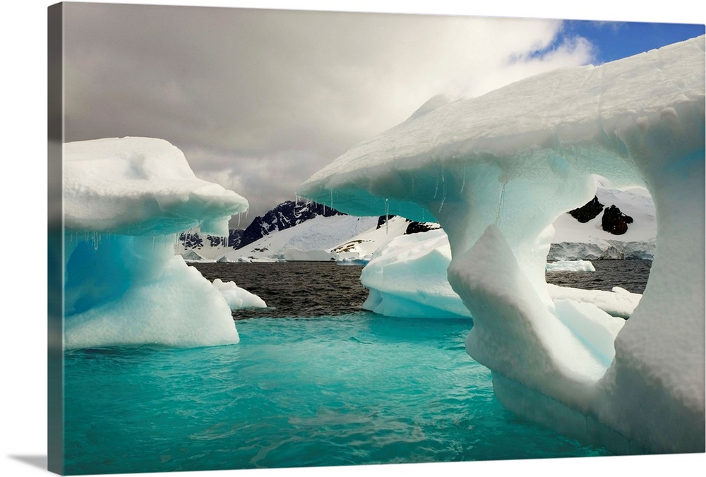 Sculpted icebergs under clouds near the shore of Couverviller Island.