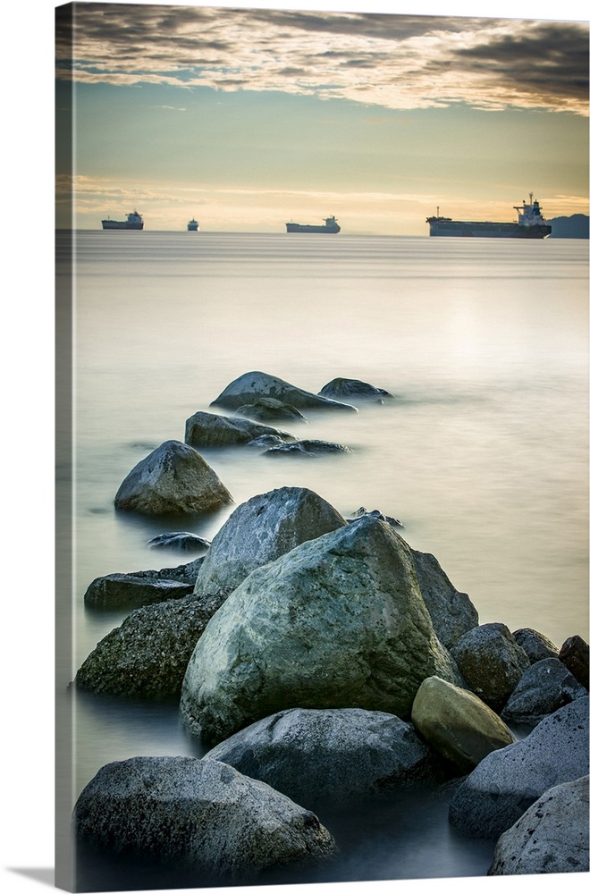 Ships out in the Pacific ocean off the coast of Stanley Park with rocks in the foreground; Vancouver, British Columbia, Ca...