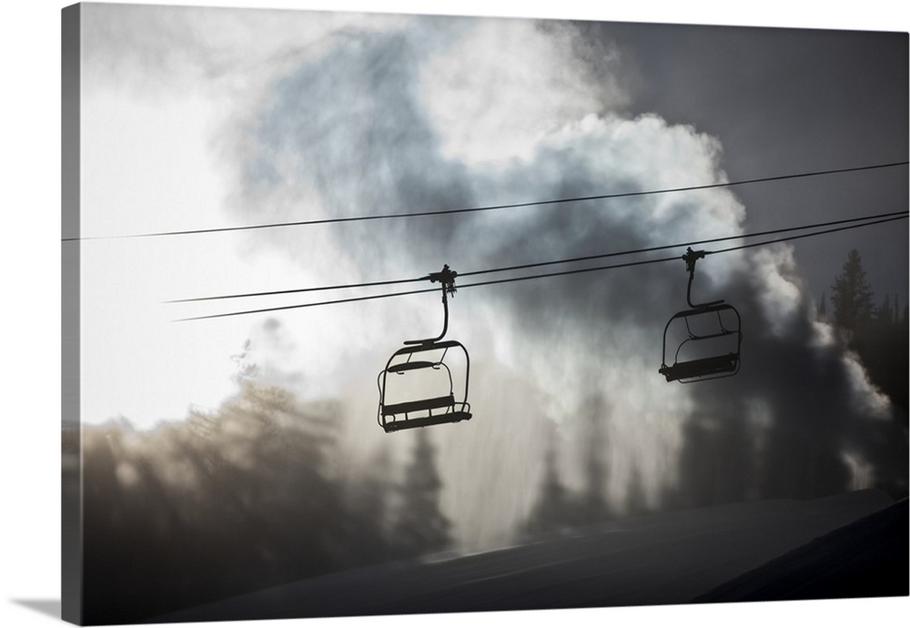 Silhouette of a chairlift on a ski hill with man made snow from  snow gun backlit by the sunlight, Copper Mountain Resort;...