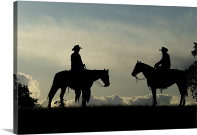 Silhouette Of Two Cowboys On Horses Against A Cloudy Sky, Montana