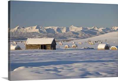 Snow Covered Log Cabin With Snow Covered Mountains; Okotoks, Alberta, Canada