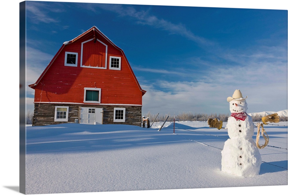 Snowman dressed up as a cowboy standing in front of a vintage red barn
