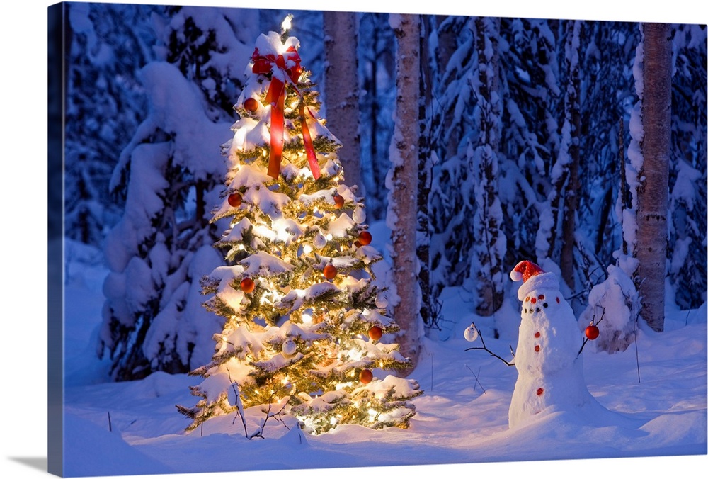 Snowman with Kris Kringle hat holding decorations next to a tree with ribbons, lights, and other embellishments in a snow ...