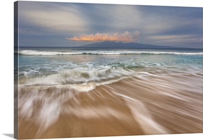 Soft water stretches across the sand at sunrise with a view of Molokai; Maui, Hawaii