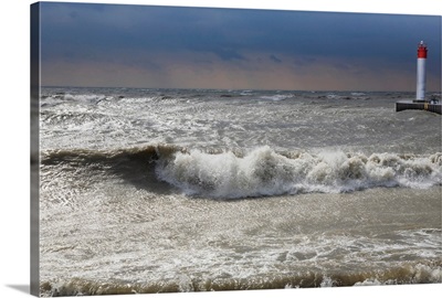 Storm waves crashing on a beach near a lighthouse on Lake Ontario, Whitby, Ontario