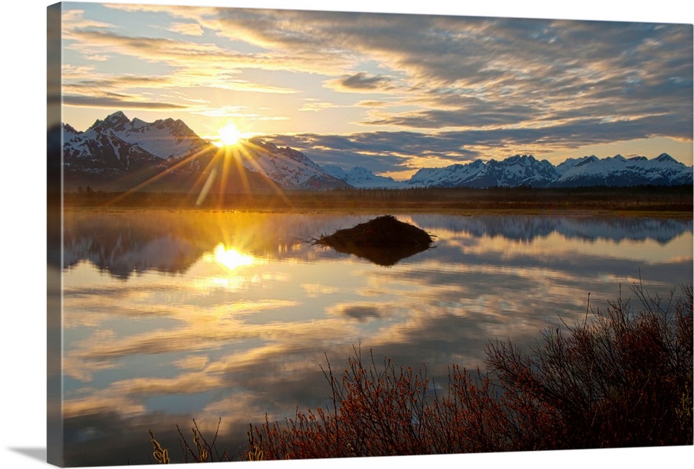 Sun rises over the Chugach Mountains at a pond with a beaver lodge along the Copper River Highway in the Chugach National ...