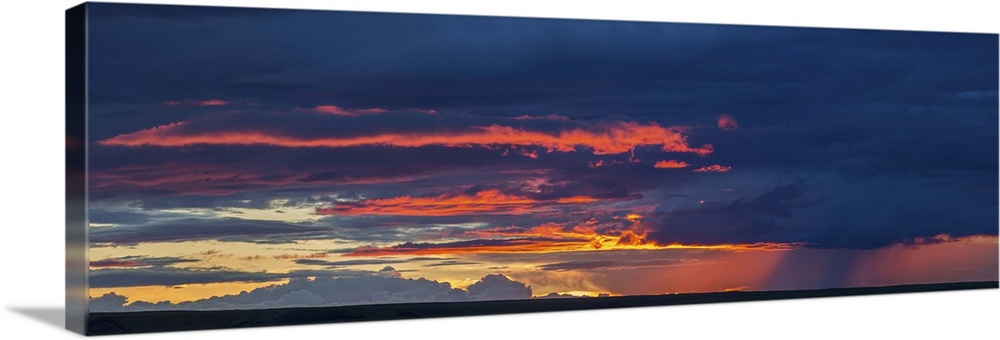 Panoramic view of sunset lit clouds and a rain shower over Grasslands National Park, Saskatchewan, Canada.