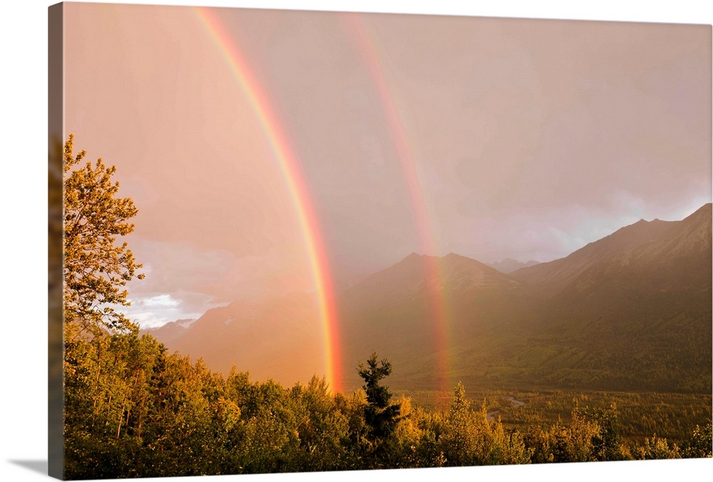A double rainbow from a passing summer evening storm in Eagle River Valley is illuminated by the setting sun in Southcentr...