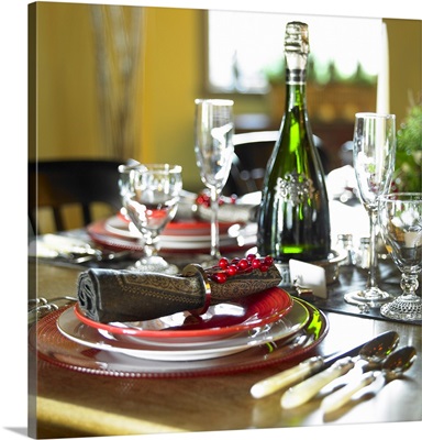 Table Setting With Red And White Plates, Red Berries On Napkin Ring And Champagne Bottle