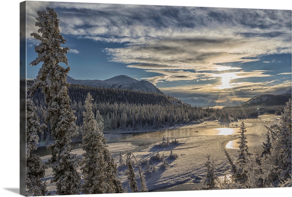 The sun breaks through the clouds above the Takhini River on a late winter afternoon, near Whitehorse. Yukon, Canada.