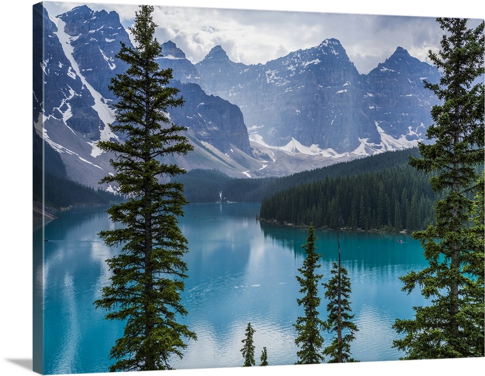 Stunning view of the rugged Canadian rocky mountain peaks and a tranquil turquoise Moraine Lake with forests along the sho...