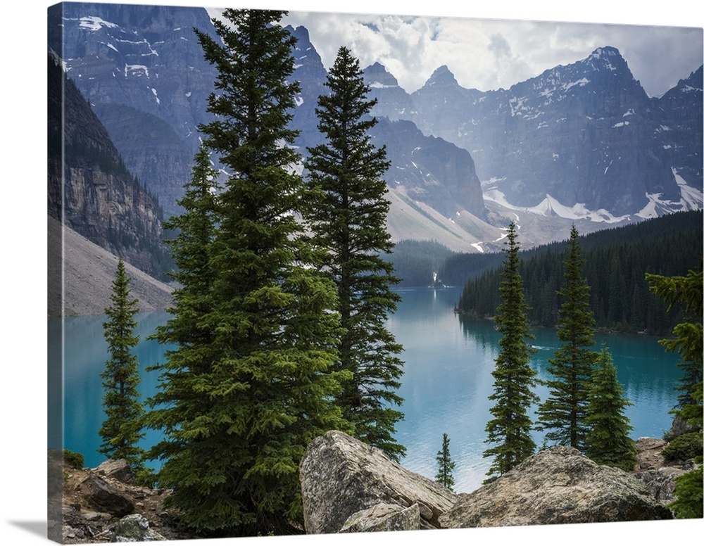 Stunning view of the rugged Canadian rocky mountain peaks and a tranquil turquoise Moraine Lake with forests along the sho...