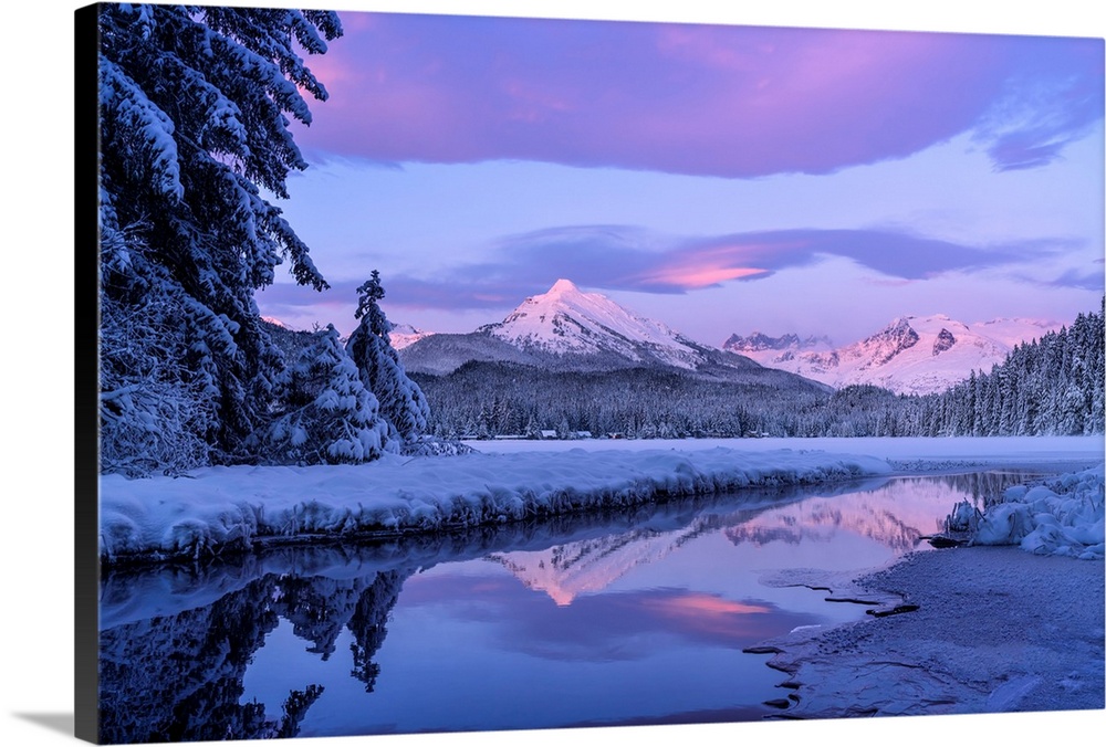 Alpenglow colours the snow-covered coastal range mountains, Mendenhall Glacier and Mendenhall towers are reflected in the ...