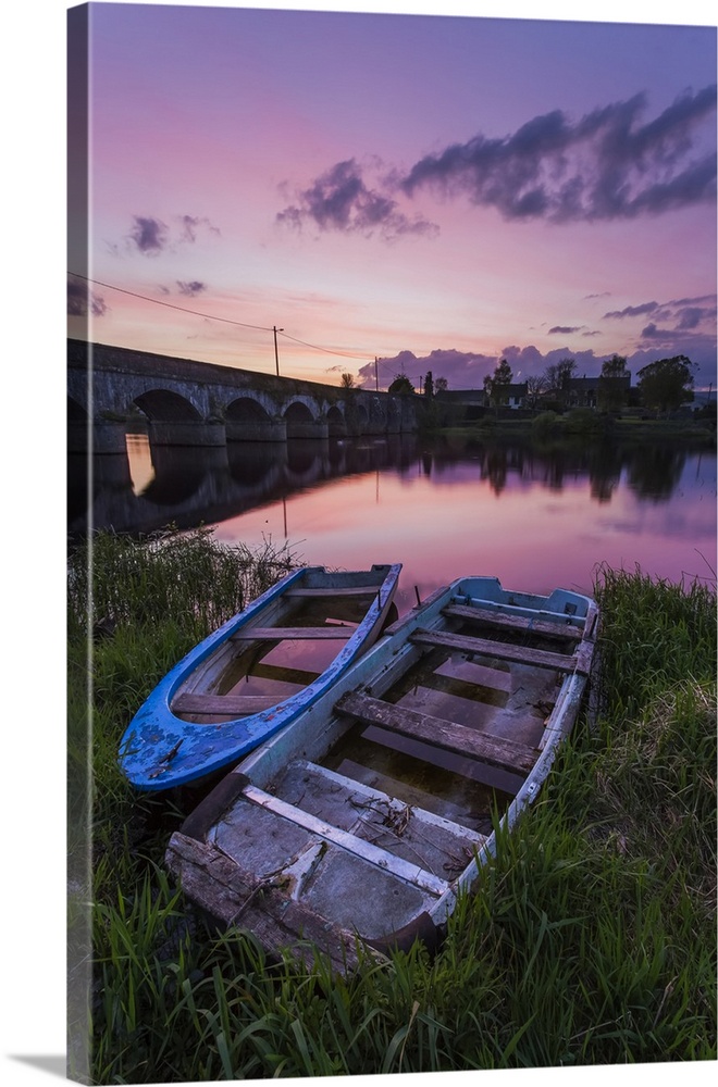 Two old wooden boats on the banks of the Shannon River at sunset with a stone bridge in the background; Montpellier, Count...