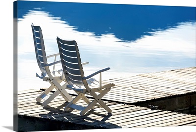 Two white wooden deck chairs on wooden boat dock