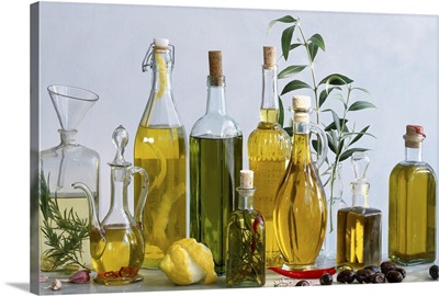 Various types of olive oils in bottles with herbs, lemon and olives