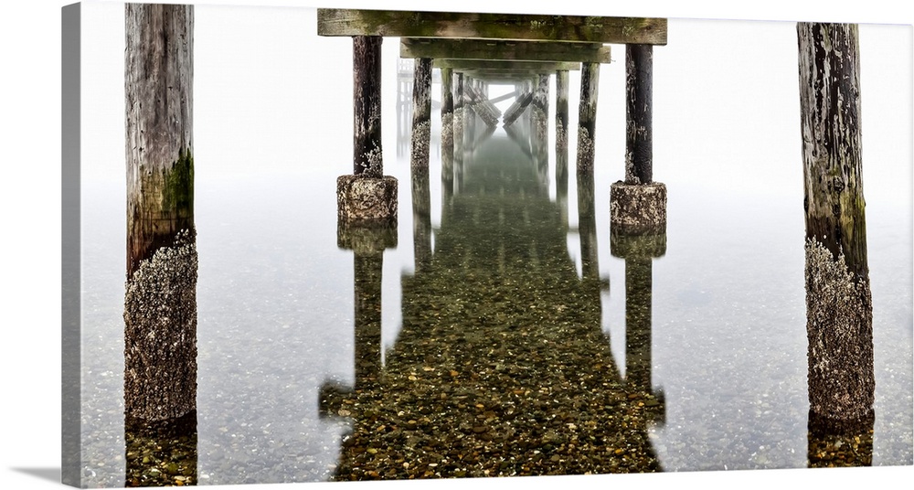 View underneath the pier on foggy crescent beach to the reflection on the shallow, clear water, surrey, British Columbia, ...