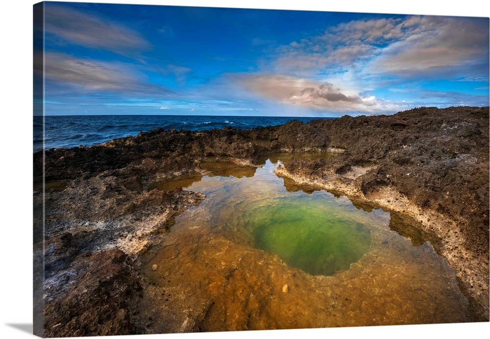 Volcanic rock formations and sunlight reflecting in the green tidal pool on the beach at Pointe des Chateaux, Grande-Terre...
