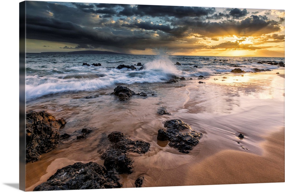 Water splashing on the beach with a golden sunset over the ocean; Hawaii, United States of America