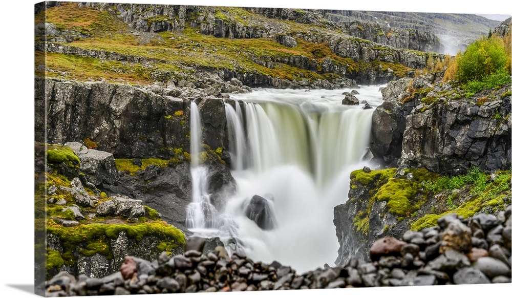 A waterfall over a rocky landscape in autumn colours; Djupivogur, Eastern Region, Iceland.